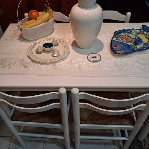 White wooden dining set used with 4 chairs with cane seats