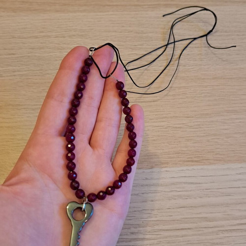 Necklace with black cord, burgundy polygonal beads and hematite key pendant like new