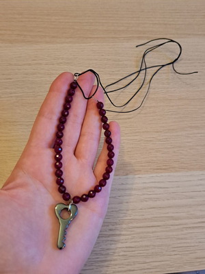 Necklace with black cord, burgundy polygonal beads and hematite key pendant like new