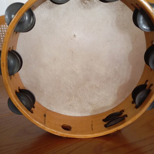 Tambourine used with natural skin, wooden frame, and metal jingles
