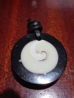 Round pendant like new with spiral design and leather cord