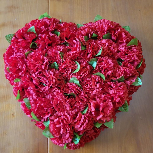 Heart made of artificial red flowers like new