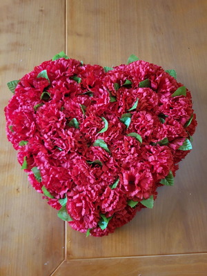 Heart made of artificial red flowers like new