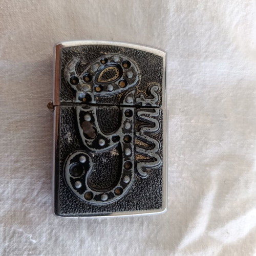 Windproof lighter with embossed metal emblem used