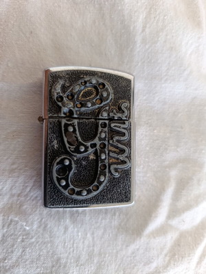 Windproof lighter with embossed metal emblem used