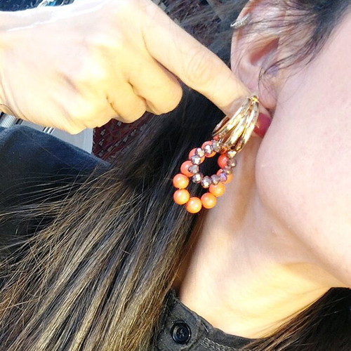 Handmade earrings with orange and purple beads on gold triple hoops