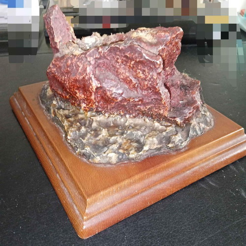 Decorative used piece with red mineral stone on wooden base