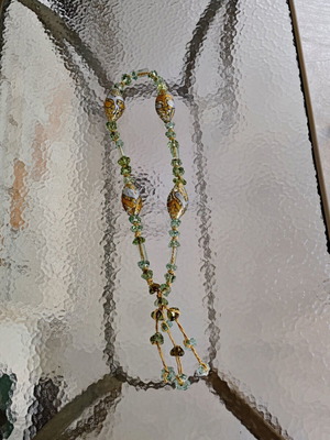 Tabletop komboloi with green and gold glass beads