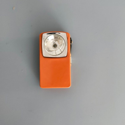 Vintage orange flat pocket flashlight used with retro UCAR battery