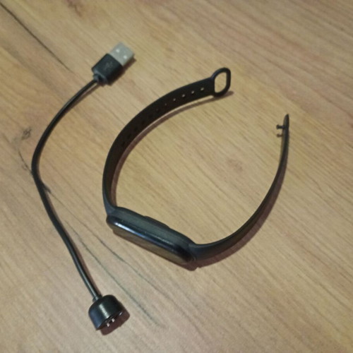M6 Smart Band fitness tracker used with charging cable