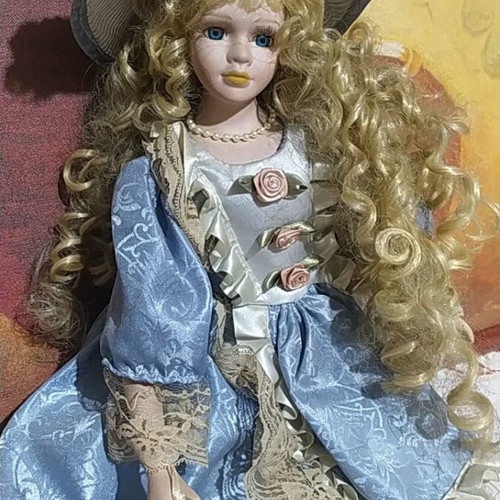 Porcelain Victorian-style doll with curly blonde hair and blue lace dress
