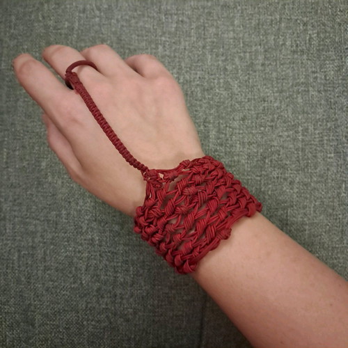 Red knitted bracelet with ring used