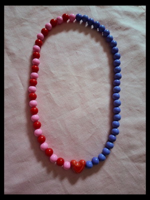 Beaded necklace with red, pink and purple beads and ceramic heart