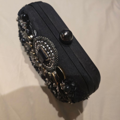 Black handheld evening bag used with small missing stone
