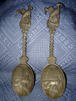 Two large decorative pewter spoons used with intricate animal designs
