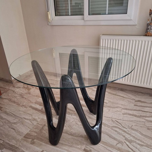Oval dining table with tempered glass top and sculptural black base
