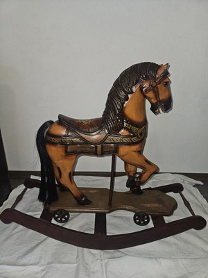 Vintage hand-carved wooden rocking horse on platform with rockers and wheels used