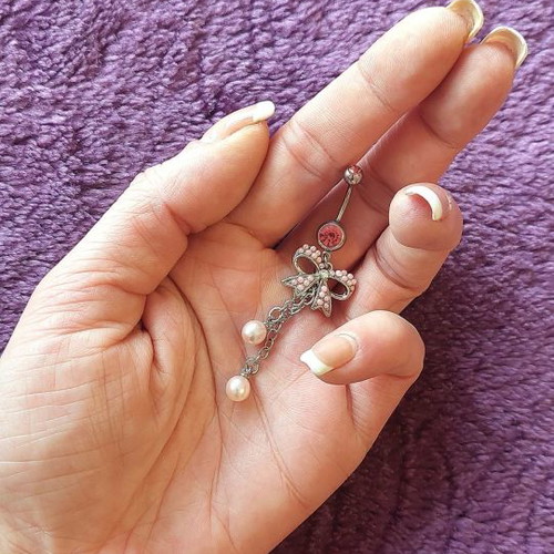 Girlie navel piercing with pink details and bow
