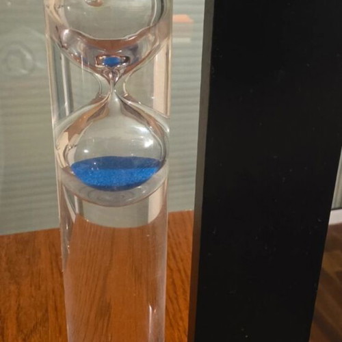 Decorative hourglass with blue sand, black wooden base