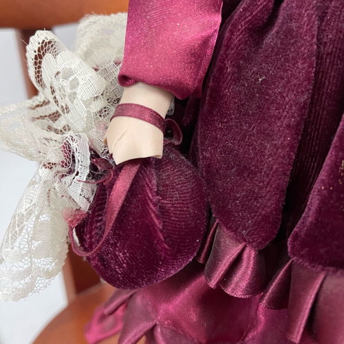 Porcelain doll used with satin and velvet dress, broken arm
