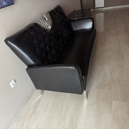 Black three-seater sofa with tufted back and metal base