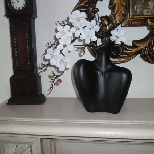 White orchid and black plastic vase shaped like female bust
