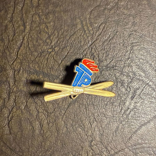 Vintage metal ski pin with crossed skis and flame