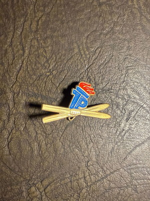 Vintage metal ski pin with crossed skis and flame