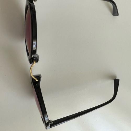 Sunglasses with round iridescent lens used, black frame with gold detail