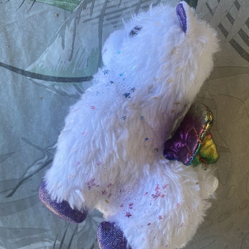 Unicorn plush toy with colorful shiny wings and metallic purple details