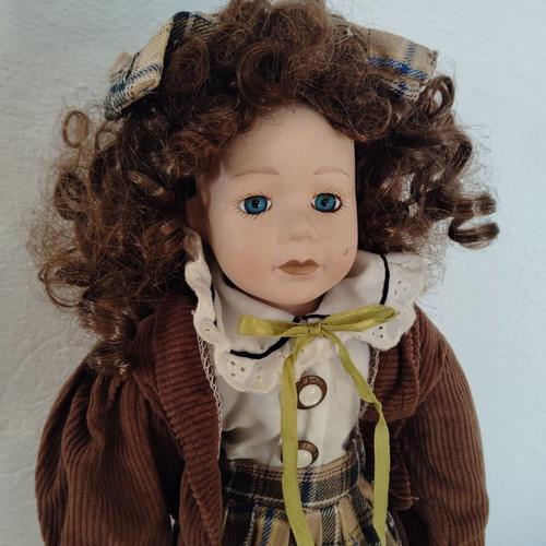 Porcelain doll like new with curly brown hair and fabric clothes