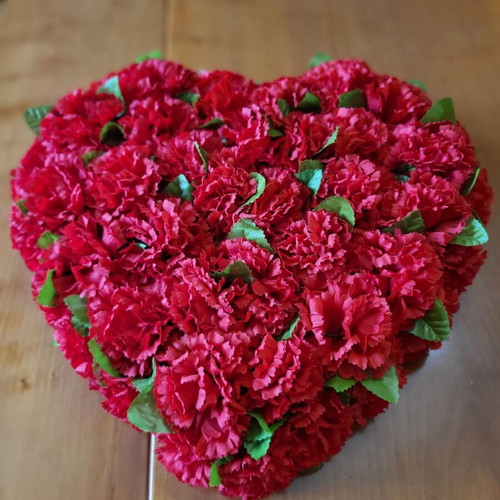Heart made of artificial red flowers like new