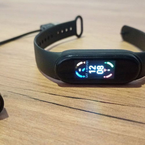M6 Smart Band fitness tracker used with charging cable