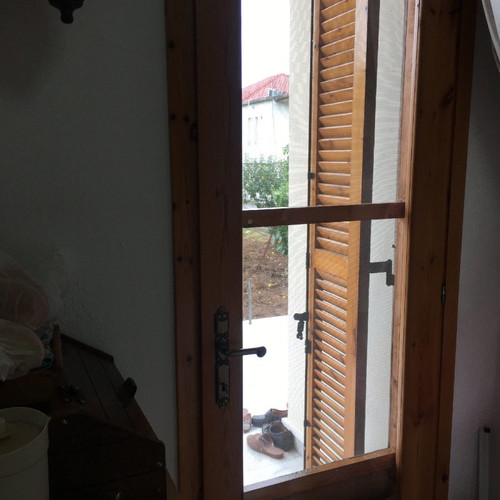Village-style balcony doors and wooden window used with screen