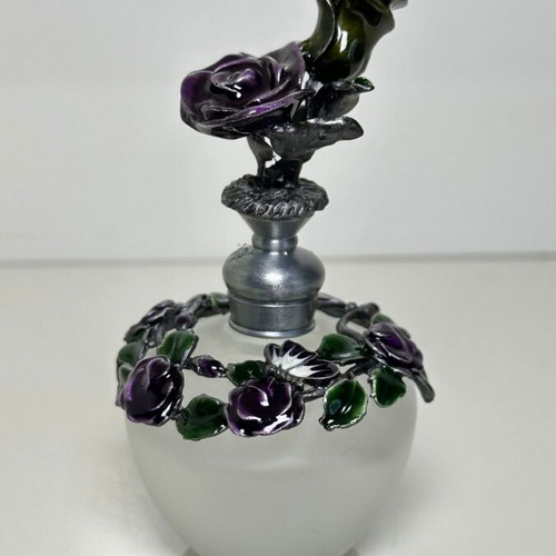 Vintage ornate perfume bottle with frosted glass and metal floral decoration