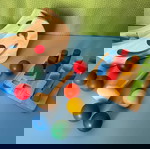  2 Βρεφικά ξύλινα παιχνίδια Plan Toys. Θαυματουργός πάγκος σε σχήμα μισοφέγγαρου με 8 χρωματιστές μπάλες και Βάση γεωμετρικών σωμάτων.