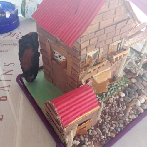Handmade decorative house with cardboard, pebbles and driftwood, new