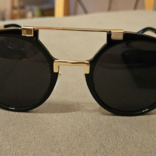 Modern sunglasses with gold frame and black round lenses