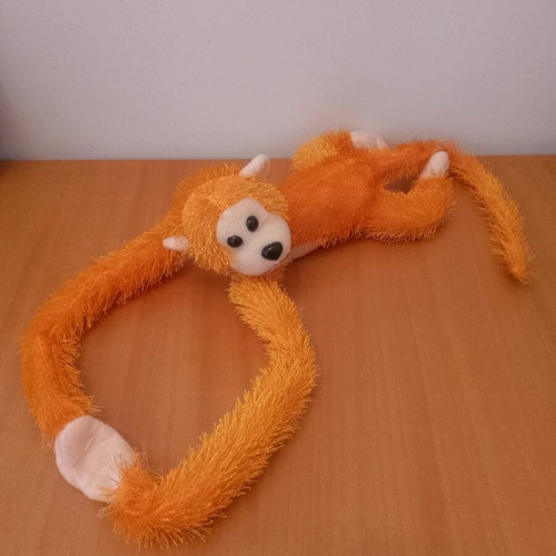 Stuffed monkey with scratches like new, orange color
