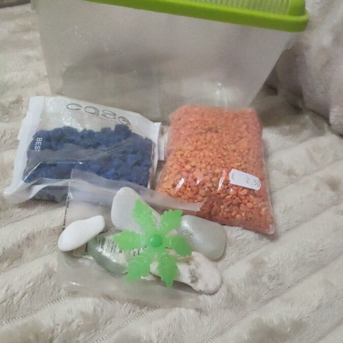 Plastic aquarium used with orange and blue gravel and accessories