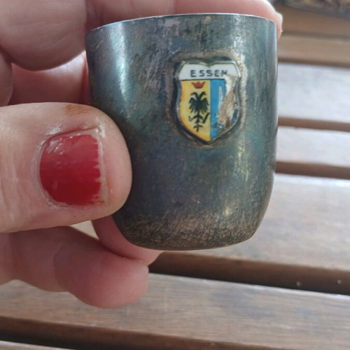 Silver shot glass used, with missing part on emblem