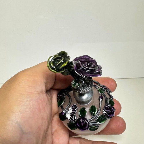 Vintage ornate perfume bottle with frosted glass and metal floral decoration