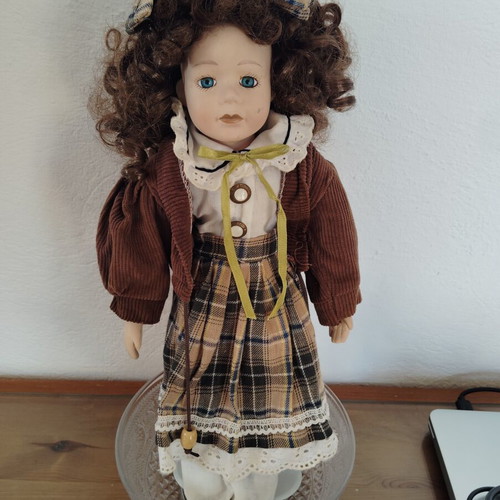 Porcelain doll like new with curly brown hair and fabric clothes