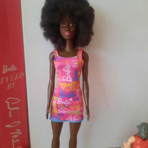Barbie doll with afro hair and pink logo dress