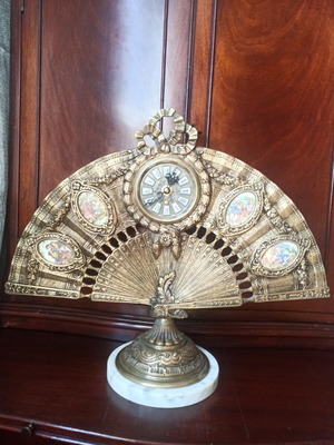 Brass fan-shaped clock with marble base and porcelain decorations