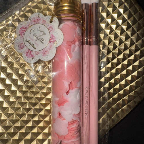 Gold makeup bag with two unused brushes