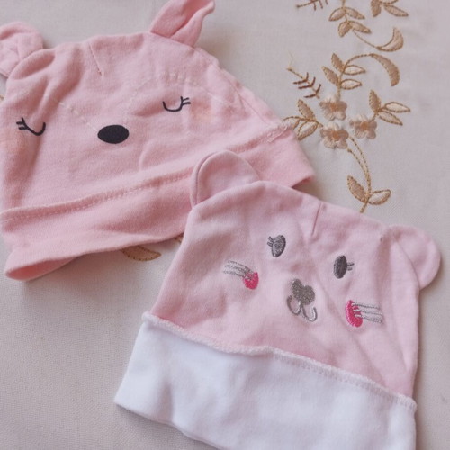 Two baby hats, one with a hole