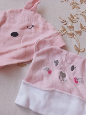 Two baby hats, one with a hole