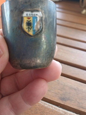 Silver shot glass used, with missing part on emblem