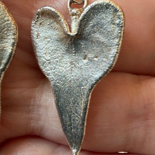 Heart-shaped dangling earrings used, silver color